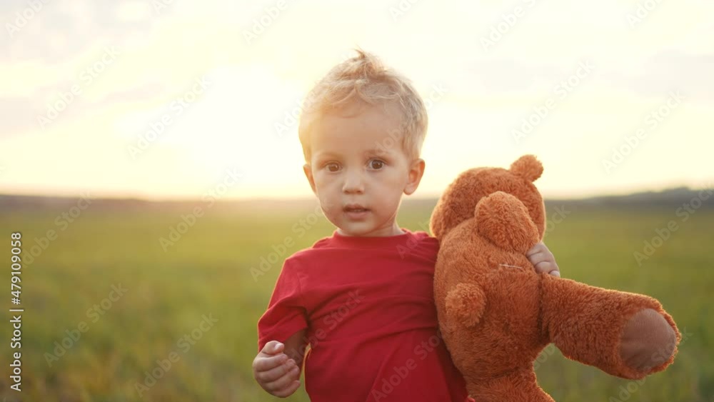portrait of a baby boy with a toy teddy bear in his hands on nature in ...