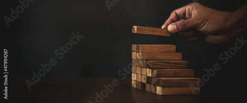 Canvas Close-up hand is placing wood block tower stacked in stair step with caution to prevent collapse or crash concepts of financial risk management and strategic planning