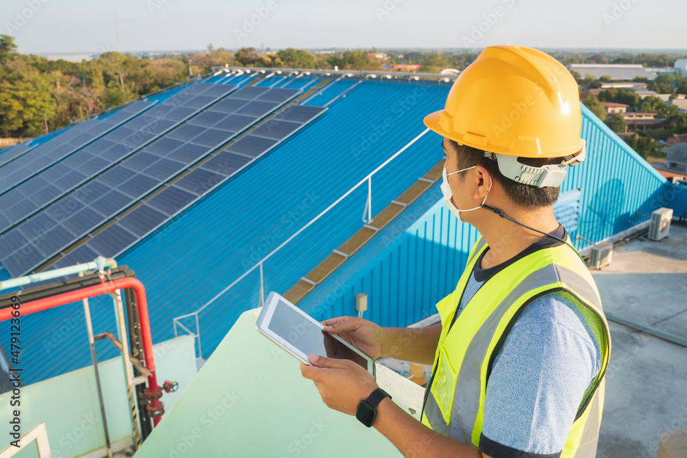 An engineer working using tablet computer to examining photovoltaic inspect solar roof panels on the roof house where solar panels installed using solar energy.Concept of alternative energy service An engineer working using tablet computer to examining photovoltaic inspect solar roof panels on the roof house where solar panels installed using solar energy.Concept of alternative energy service