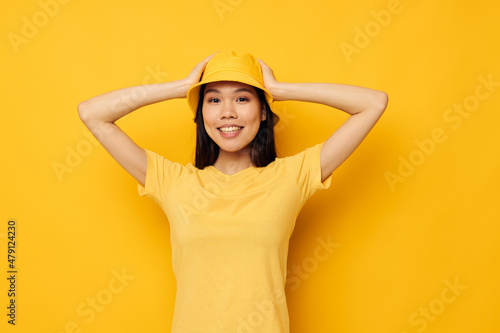 Charming young Asian woman wearing a yellow hat posing emotions yellow background unaltered © Tatiana