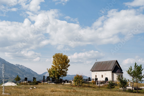 Old chapel near the cemetery in the field against the background of mountains