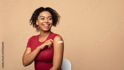 Print op canvas Cheerful vaccinated black woman showing arm with bandage after coronavirus vacci