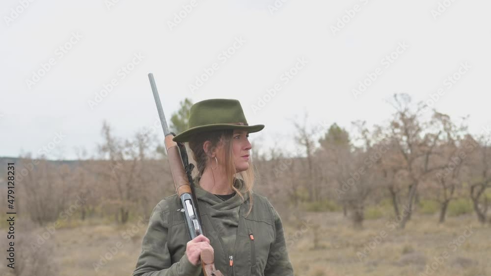 Hunter woman with shotgun hunting in the field.