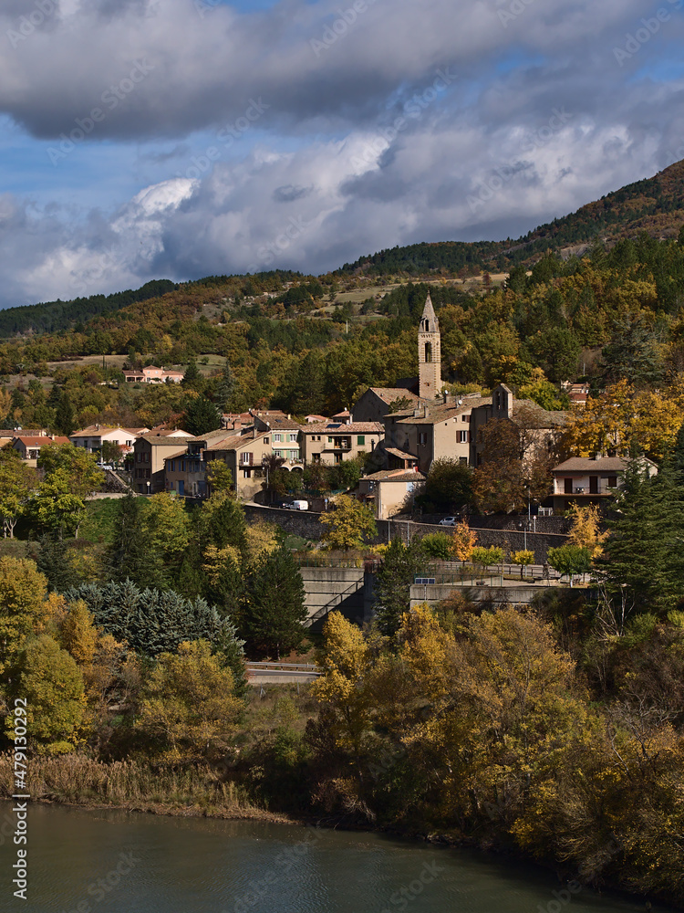 Beautiful view of small village with church and traditional buildings, part of town Sisteron, Provence, France, surrounded by colorful trees in autumn.