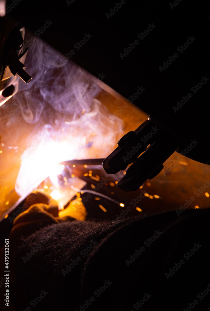 Close-up of a welder working in a workshop. Welding inside a metal structure.