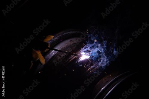 Close-up of a welder working in a workshop. Shallow depth of field. Welding of metal structures. Metal welding. Semi-automatic manual welding. MIG welding.