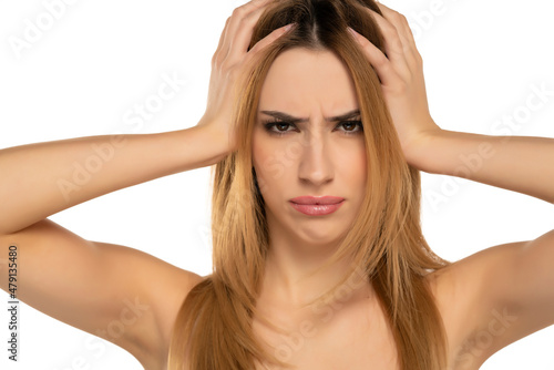 young woman looks at camera holding head in hands feels unhealthy stressed