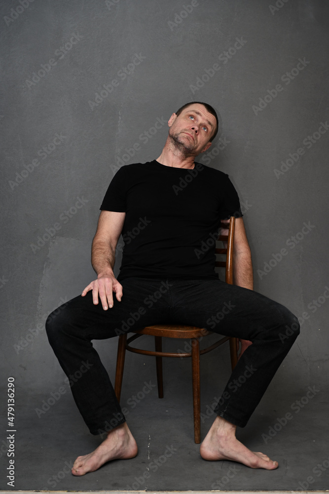 Adult male man on a gray background looking up while sitting on a chair