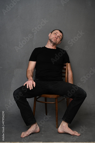 Adult male man on a gray background looking up while sitting on a chair