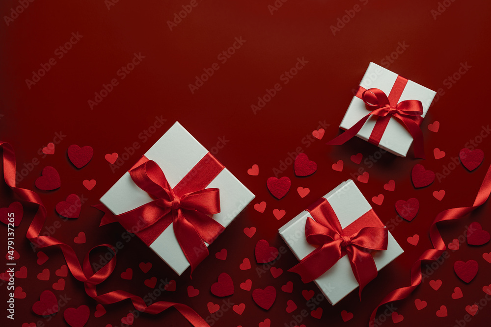 Presents with red bow on red background with heart confetti. Flat lay style. Valentine day concept. Saint VAaentines Presents with red bow on red background with heart confetti. Flat lay style. Valentine day concept. Saint VAaentines