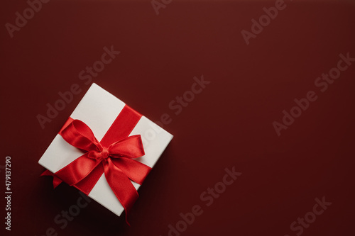 Presents with red bow on red background with heart confetti. Flat lay style. Valentine day concept. Saint VAaentines