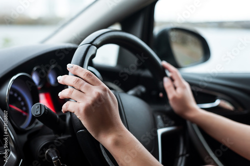 Women's hands on the steering wheel, inside the car. © Evgeny Leontiev