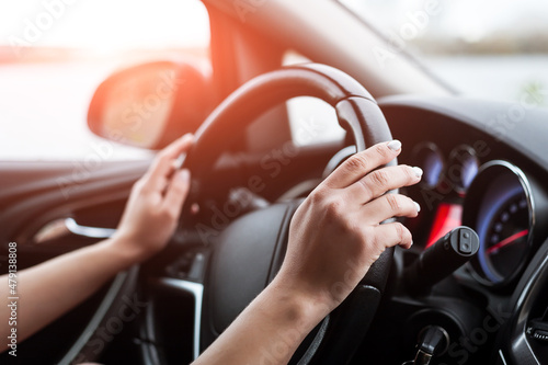 Women's hands on the steering wheel, inside the car.