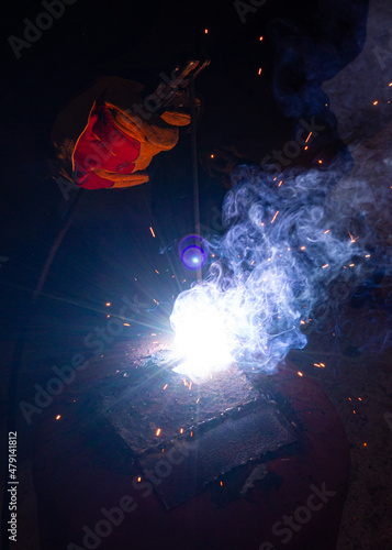 Welder in a glove with a welder in his hands works welding. Metal welding. Welding flame with sparks. © Виктор Лазарев