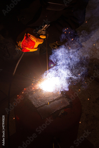 Welder in a glove with a welder in his hands works welding. Metal welding. Welding flame with sparks.