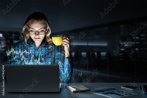 Beautiful blonde working on laptop and infographs out of screen. Mixed media