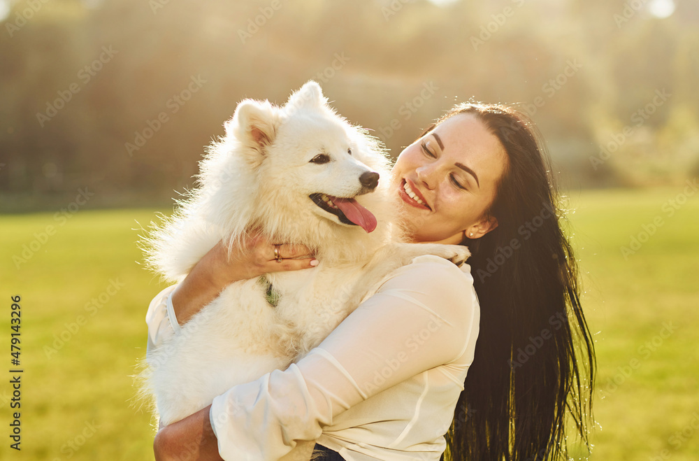 Woman is sitting on the ground of field with her cute dog Woman is sitting on the ground of field with her cute dog