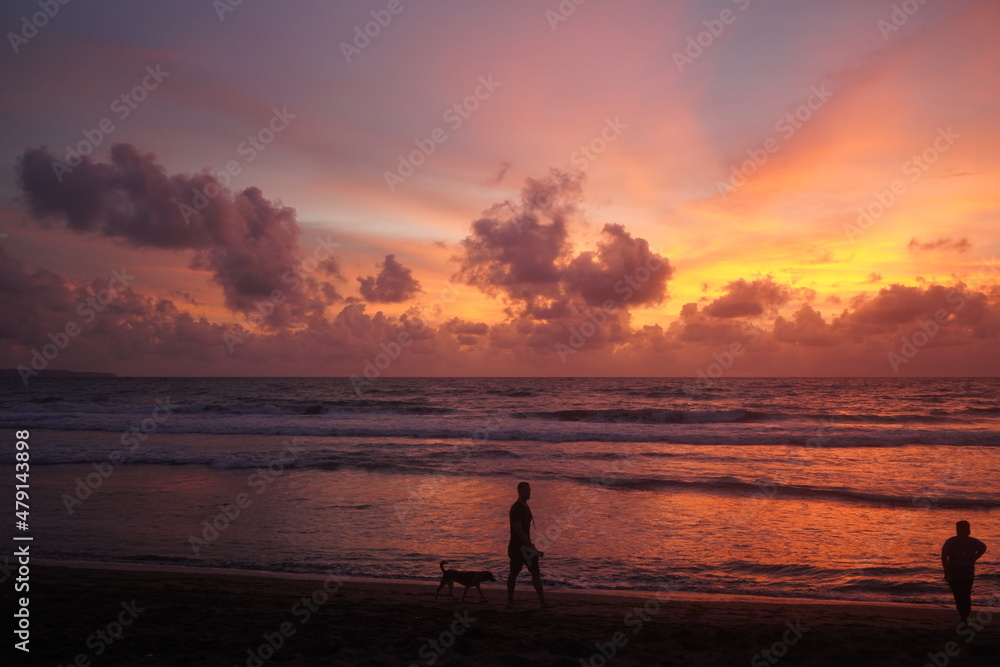 silhouette of a man on the ocean beach at sunset, winter in Bali, red-orange clouds
