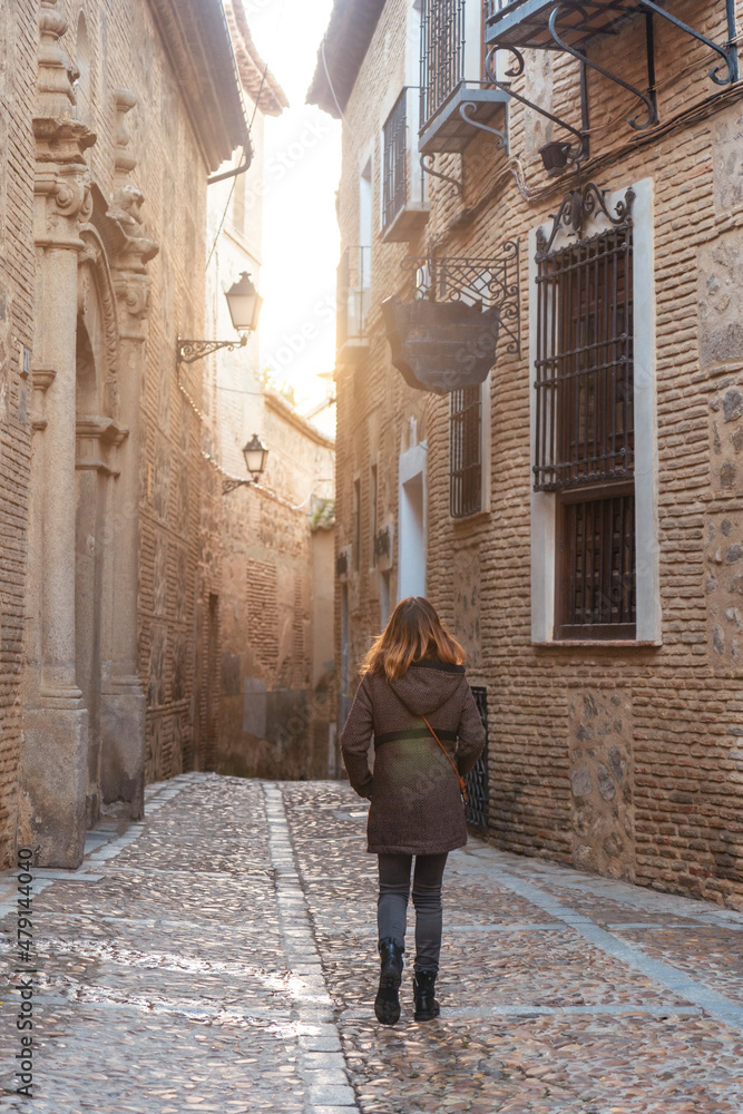 A tourist walking at sunset in the medieval city of Toledo in Castilla La Mancha, Spain