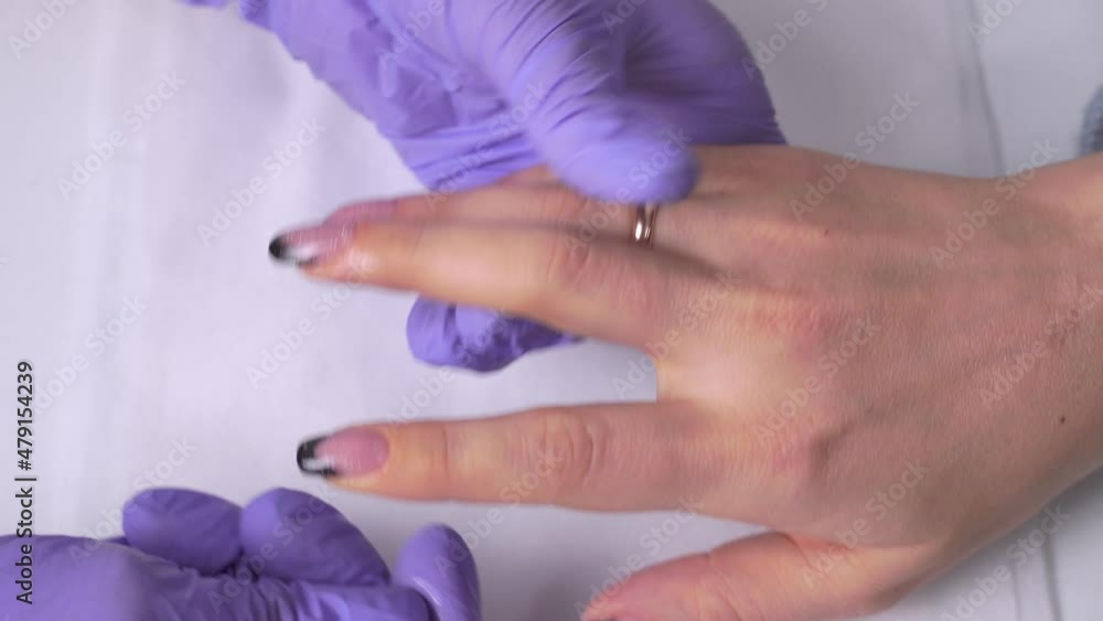 Close-up of the manicure master rubbing oil on the cuticle of the client. Close-up of the manicure master rubbing oil on the cuticle of the client.