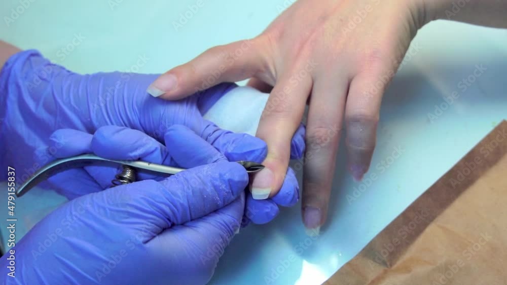Close-up of manicure master doing a manicure to woman, cutting off the cuticle Close-up of manicure master doing a manicure to woman, cutting off the cuticle