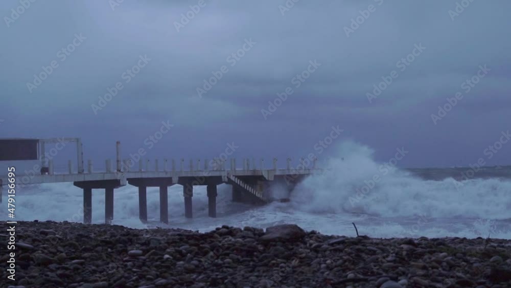 Storm waves crash against old reinforced concrete pillars on the beach Storm waves crash against old reinforced concrete pillars on the beach