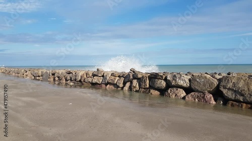 Huge boulders on sandy seashore 	Huge boulders on sandy seashore to prevent coastal land erosion photo