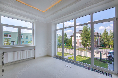 An empty  bright  unfurnished living room with a high ceiling and a panoramic window. New modern house without furniture