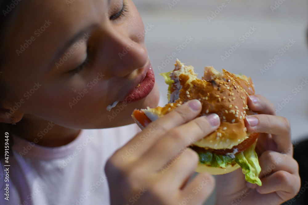 girl eating delicious fast food hamburger with fries.