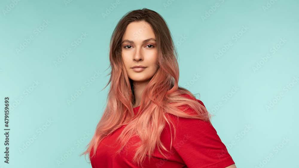 Obraz premium Portrait of a beautiful young woman in a red t-shirt on a blue background in the studio