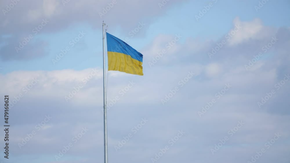 The large flag of ukraine flies on a flagpole against the sky, slow motion The large flag of ukraine flies on a flagpole against the sky, slow motion