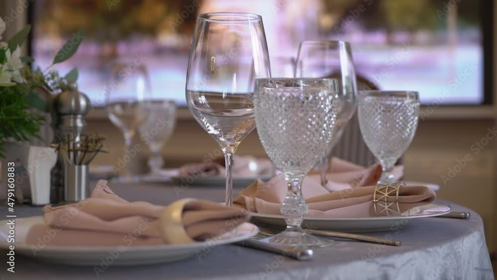 Served table in a restaurant for dinner, lunch or celebration. White tablecloth, plates, pink napkins and glasses, chairs. Holiday indoors. Empty with no people and food. Decorated for wedding. Served table in a restaurant for dinner, lunch or celebration. White tablecloth, plates, pink napkins and glasses, chairs. Holiday indoors. Empty with no people and food. Decorated for wedding.