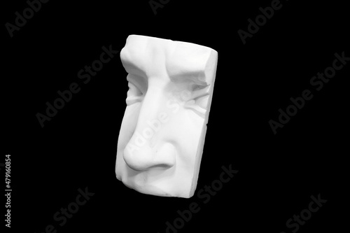 Fragment of plaster sculpture of a human face isolated on black background