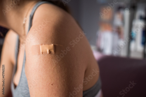 New York, USA - January 2022. Person's Left Arm With Adhesive Bandage After COVID-19 Vaccine. - closeup.