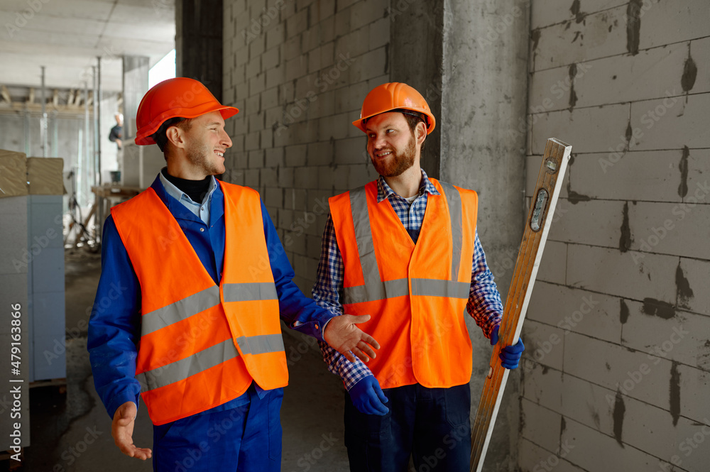 Two builders in uniform walking and talking about construction Two builders in uniform walking and talking about construction