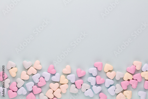 Composition with candy hearts on pastel blue background. © gitusik