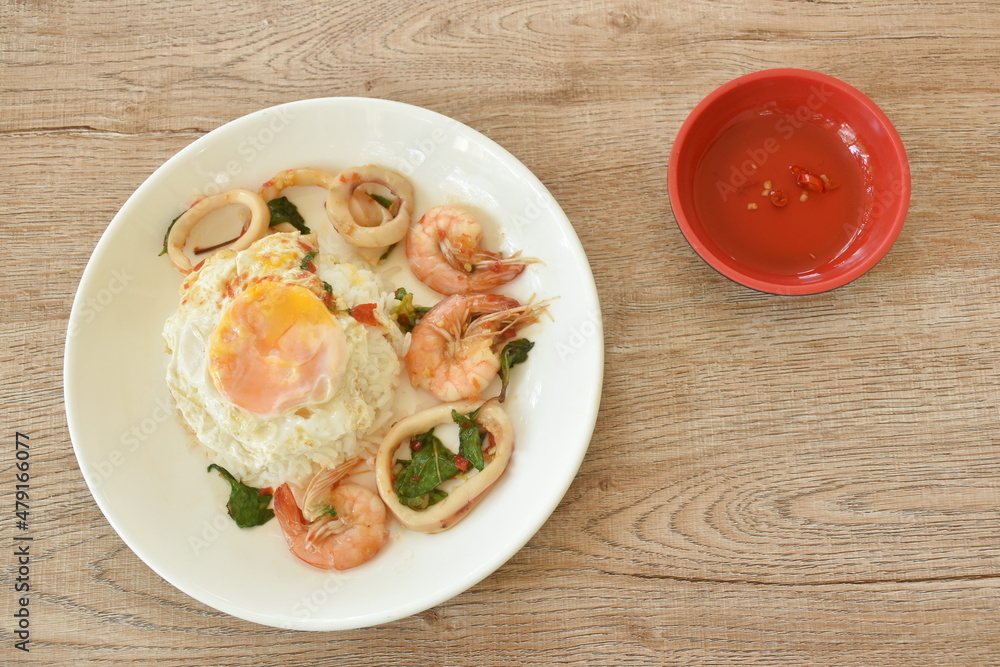 spicy stir fried shrimp and squid basil leaf topping egg eat couple with rice on plate spicy stir fried shrimp and squid basil leaf topping egg eat couple with rice on plate