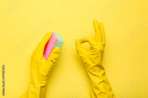 hands in gloves hold a sponge on a yellow background