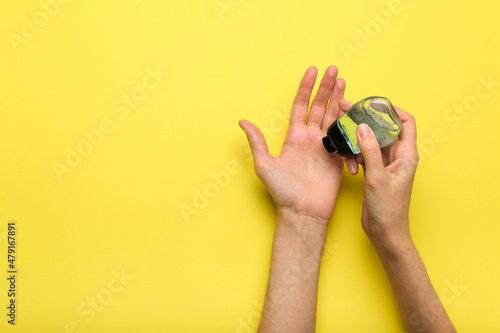 antiseptic applied to hands on yellow background