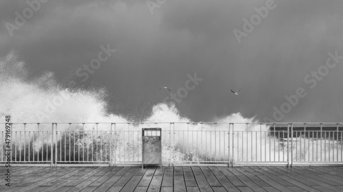 stormy waves crashing against railings against the gray stormy sky