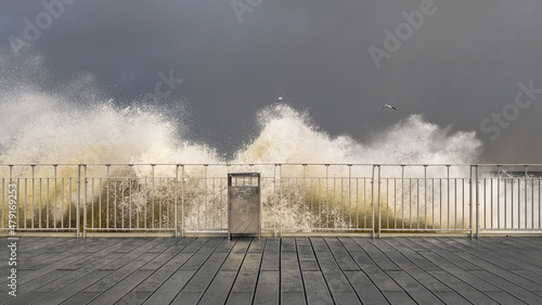 stormy waves crashing against railings against the gray stormy sky