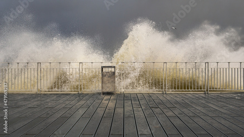 stormy waves crashing against railings against the gray stormy sky