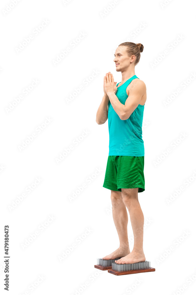 Caucasian slim man stands on Sadhu boards with sharp nails, vertical photo, isolated on white. Caucasian slim man stands on Sadhu boards with sharp nails, vertical photo, isolated on white.