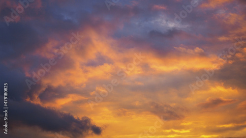 Cloudy sky at sunset. Dark violet-yellow natural background or wallpaper. The rays of the setting sun effectively illuminate the clouds. Beautiful and dramatic evening skies