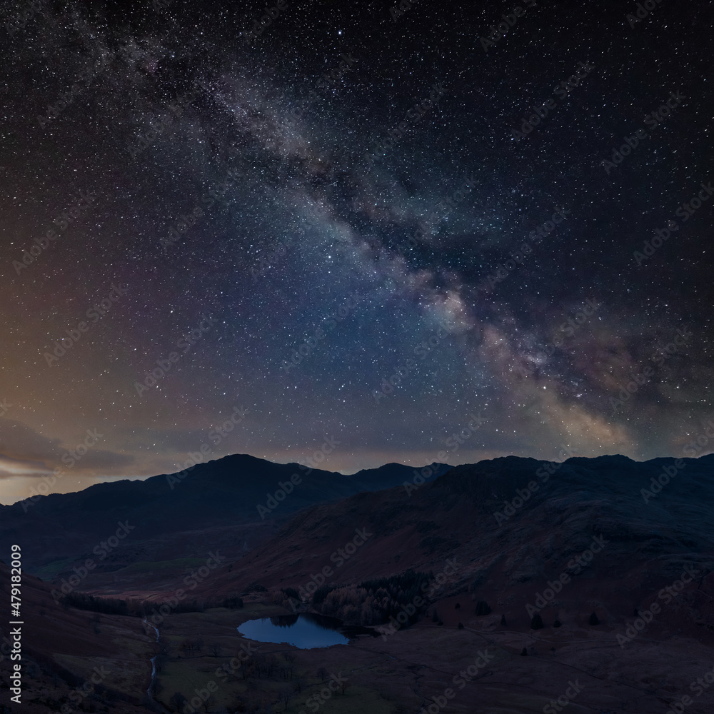 Digital composite image of Milky Way night sky over Beautiful landscape image of Blea Tarn in Lake District