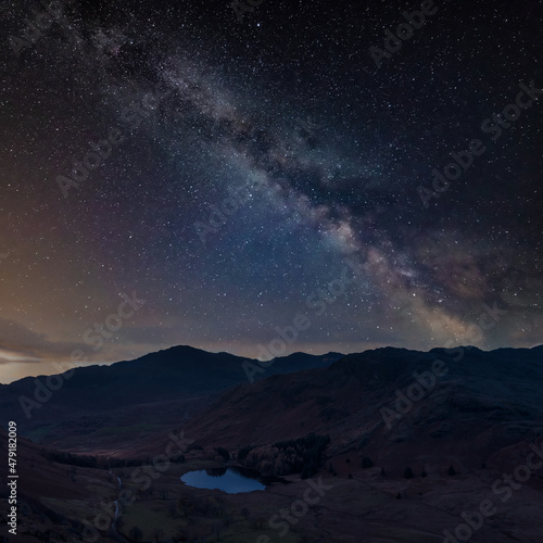Digital composite image of Milky Way night sky over Beautiful landscape image of Blea Tarn in Lake District