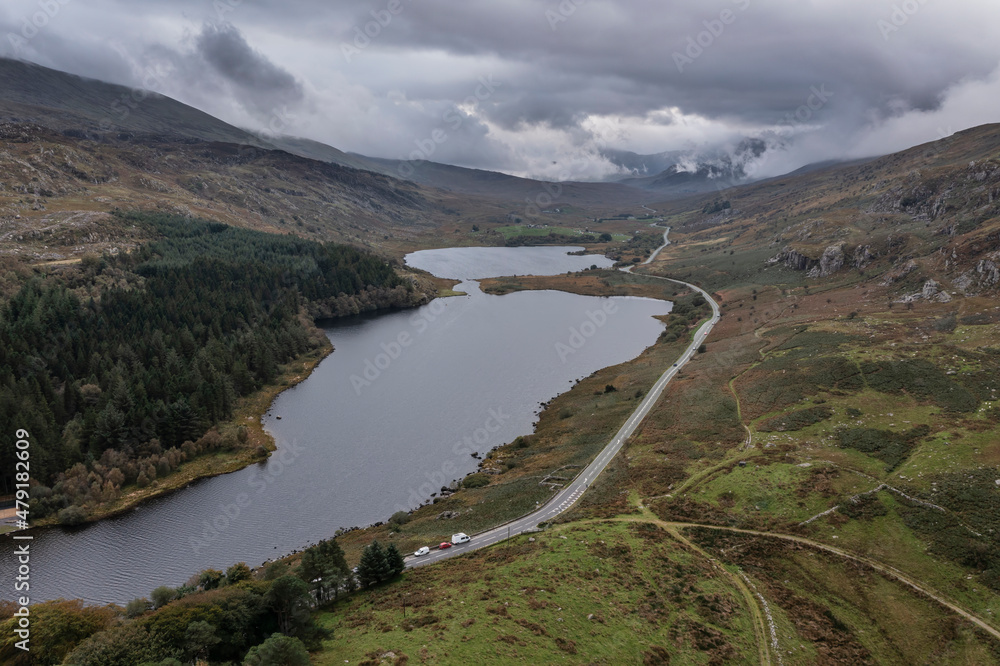 Fototapeta premium Epic aerial flying drone landscape image of Snowdon Massif viewed from above Llynau Mymber during Autumn sunset with dramatic sky