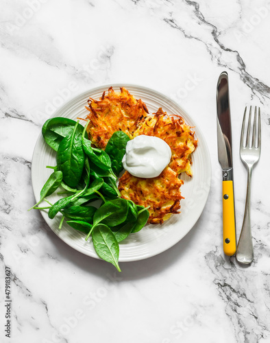 Delicious breakfast - potatoes latkes with sour cream and spinach salad on a light background, top view photo