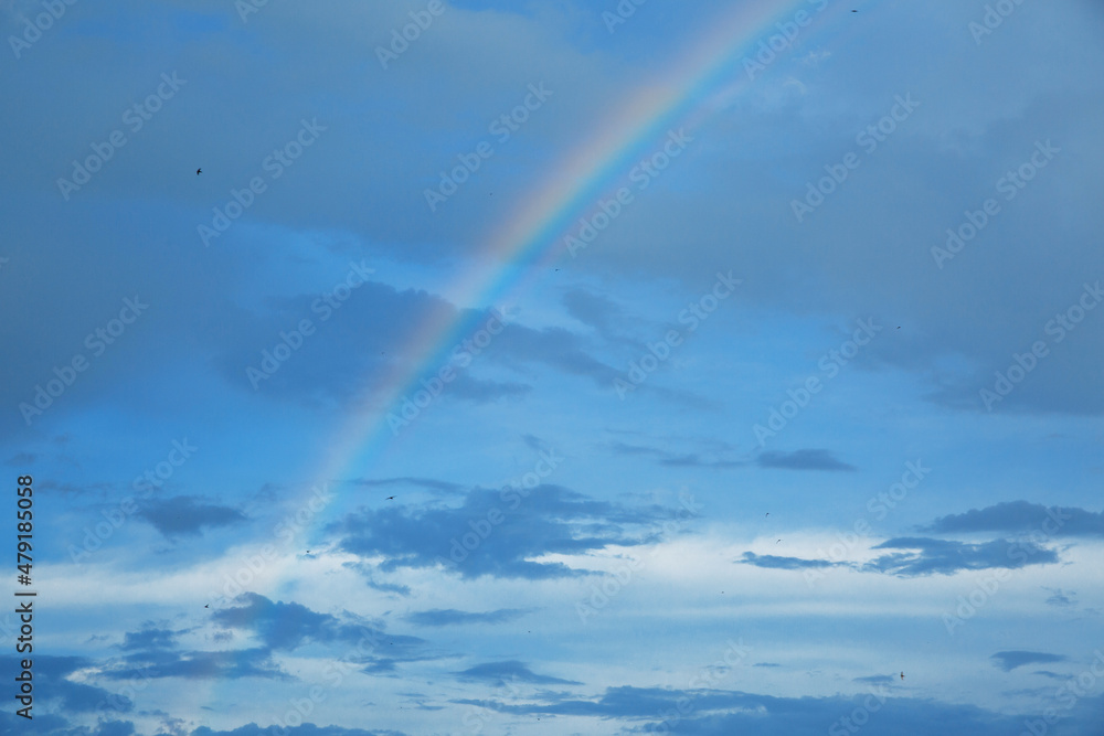Rainbow in the blue sky with clouds