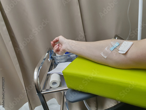 Plastic intravenous tube for woman's hand in day hospital, medical equipment. A bed in clinic, the state of health of an unrecognizable woman. The concept of dialysis disease Chovid-19.